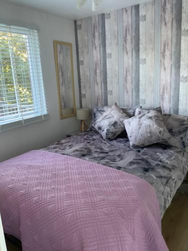 1 dormitorio con 1 cama con edredón morado y ventana en CRIB GOCH HOLIDAY CABIN SNOWDONIA en Caernarfon