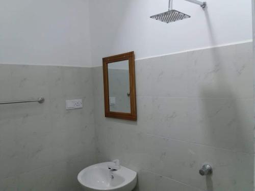 uma casa de banho com um lavatório e um espelho na parede em Panorama Holiday inn-Pelmadulla em Ratnapura
