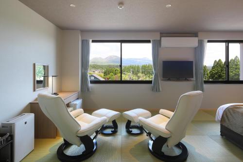 Pokój z 2 krzesłami, łóżkiem i oknami w obiekcie Aso Hakuun Sanso w mieście Aso
