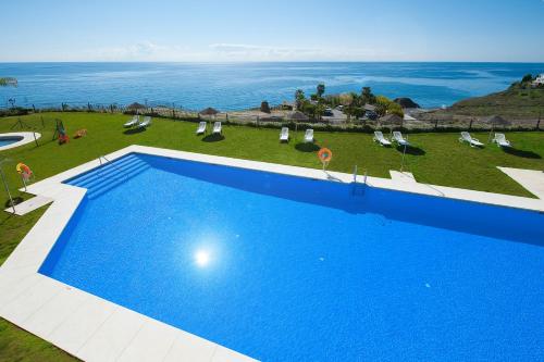 a large blue swimming pool with a view of the ocean at Olée Nerja Holiday Rentals by Fuerte Group in Torrox Costa