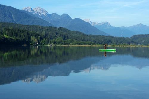 a person in a kayak on a lake with mountains at Appartment Isabelle - Kamille in Presseggersee