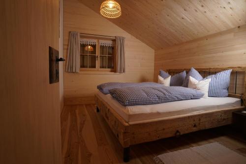a bedroom with a bed with blue and white pillows at Hirschberghütte in Bizau