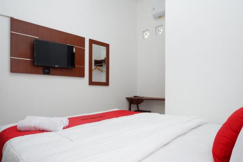1 dormitorio con 1 cama y TV de pantalla plana en la pared en RedDoorz Syariah near Exit Tol Krapyak Semarang en Kalibanteng-kidul