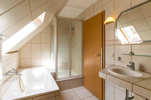 ein Badezimmer mit einem Waschbecken, einer Badewanne und einem Spiegel in der Unterkunft Landhotel Cafe Prälank in Neustrelitz