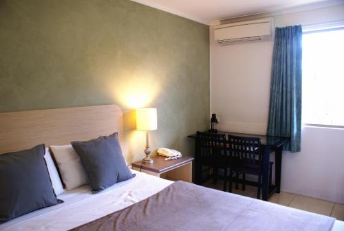 a bedroom with a bed and a chair and a window at Mackay Motor Inn in Mackay