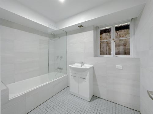 a white bathroom with a sink and a bath tub at Kent Cosy House in Sydney