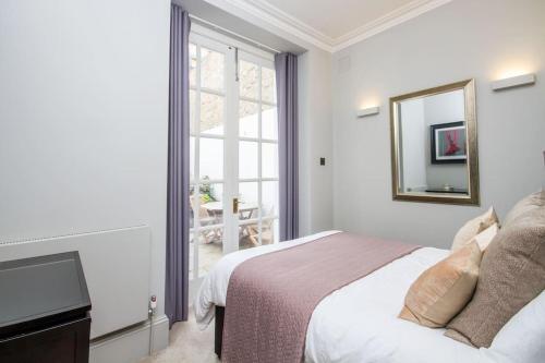a white bedroom with a bed and a mirror at Private Patio - 2 Bedroom 2 Bathroom - Russell Sq in London
