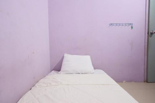 a small room with a bed and a white wall at SPOT ON 92389 Fendi Homestay Syariah in Nagoya