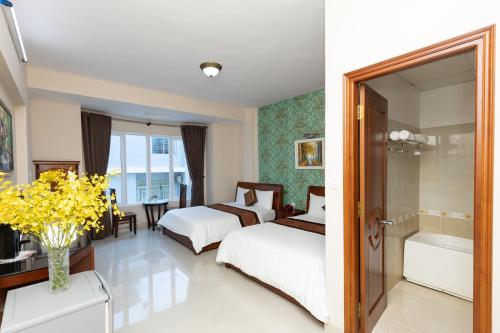 a hotel room with two beds and a bathroom at Queen Garden Hotel & Apartment in Vung Tau
