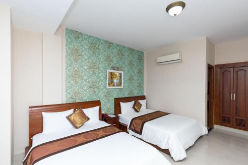 a bedroom with two beds and a wall at Queen Garden Hotel & Apartment in Vung Tau