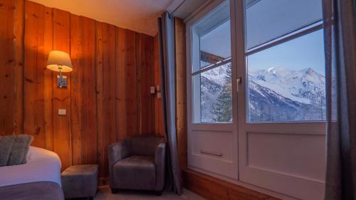 a bedroom with a door and a chair and a window at Hôtel Le Labrador in Chamonix-Mont-Blanc