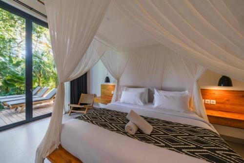 a bedroom with a white bed with a canopy at Villa Satiya - Unique and stylish 4-bdr pool villa in Pererenan! in Canggu