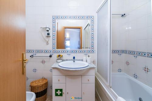ein Badezimmer mit einem Waschbecken, einer Badewanne und einem Spiegel in der Unterkunft Praia Mar - Apartamento Viva Local in Portimão
