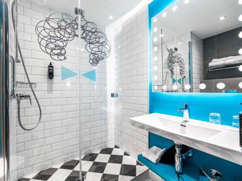een badkamer met blauwe en witte tegels en een wastafel bij ibis Styles Szczecin Stare Miasto in Szczecin