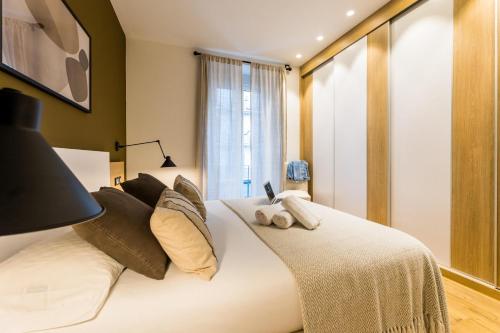 una camera da letto con un grande letto bianco con cuscini di BOULEVARD SUITE APARTMENT a San Sebastián