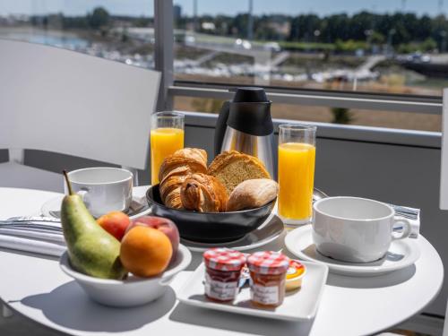 una mesa con una bandeja de alimentos para el desayuno y zumo de naranja en Westotel Le Pouliguen, en Le Pouliguen