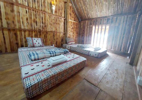 - une chambre avec 3 lits dans une cabane en bois dans l'établissement Quanba Taigoo - HomeStay, à Ha Giang