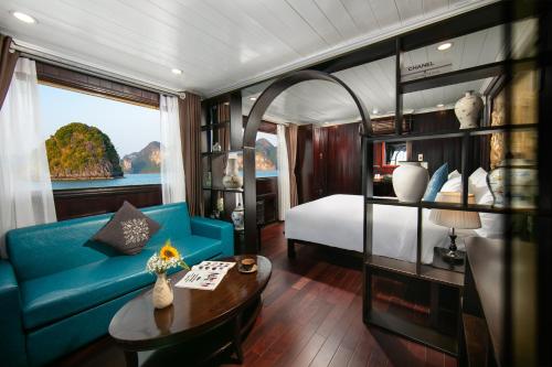 a room with a blue couch and a bed and a table at La Regina Classic Cruise in Ha Long