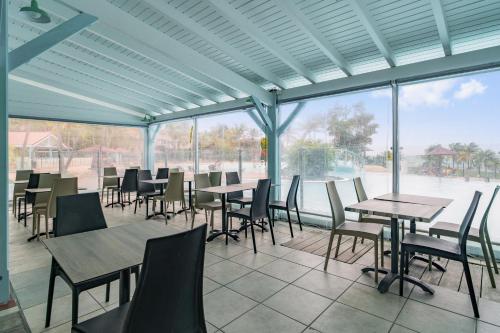 a dining area with tables and chairs and windows at Village Pierre & Vacances Sainte Anne in Sainte-Anne