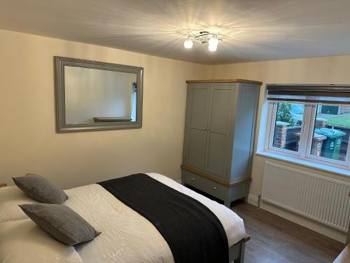 een slaapkamer met een bed, een spiegel en een raam bij The grey retreat in Shepperton