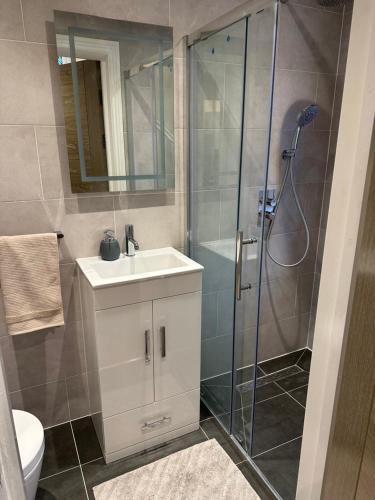 W łazience znajduje się umywalka i prysznic. w obiekcie The grey retreat w mieście Shepperton