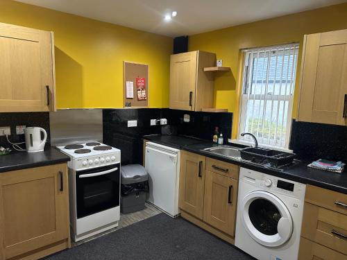 a kitchen with yellow walls and a washer and dryer at 3 Dialknowe Holiday Cottage - Wanlockhead in Wanlockhead
