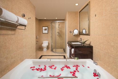 a bathroom with a tub with red flowers on it at Maoming Country Garden Phoenix Hotel in Dianbai