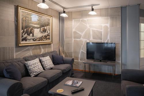 sala de estar con sofá y TV de pantalla plana en Budget Hotel Karhu, en Sodankylä
