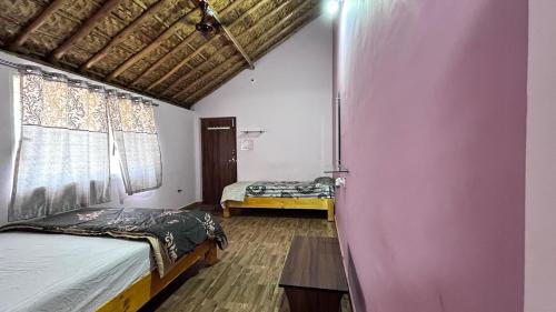 a bedroom with two beds and a pink wall at Prajwal home stay in Hampi
