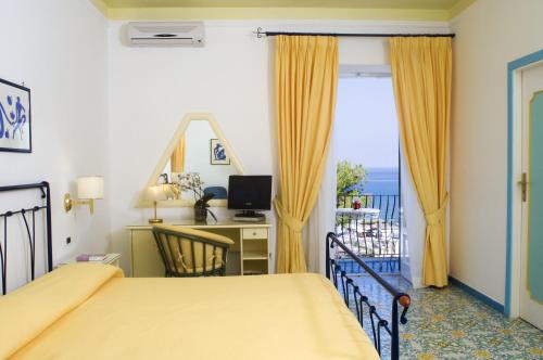 a bedroom with a bed and a desk and a window at Hotel Villa Bianca in Ischia