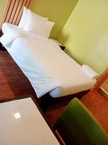 a bed with white sheets and pillows in a room at Damara Hotel at Ciudad Elmina in Dagupan