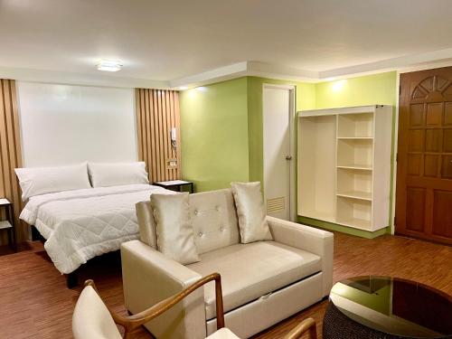 ein Wohnzimmer mit einem Bett und einem Sofa in der Unterkunft Damara Hotel at Ciudad Elmina in Dagupan