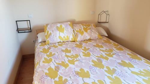 a bed with a pink and yellow comforter and pillows at La Casuca de Rosi en Suances in Suances