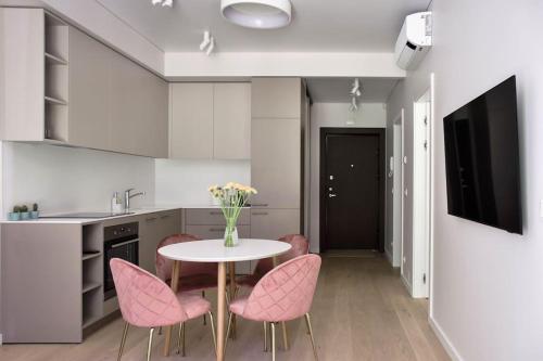 a kitchen with pink chairs and a table with a vase of flowers at Parko Aveniu Apartamentai B4 in Birštonas