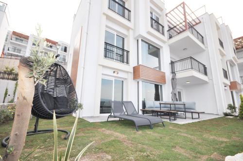 a large white building with chairs in a yard at Villa Esteban Özel Plajlı in Bogazici