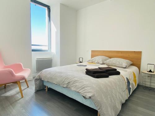 um quarto com uma cama grande e uma cadeira rosa em LE CAPUCIN em Rodez