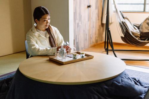 una mujer sentada en una mesa con una bandeja en Hisaeya Ryokan, en Fujioka