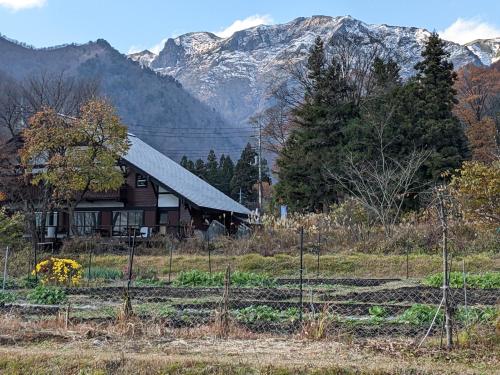 a house in a field with mountains in the background at Tanigawa Valley Lodge & Coffee Roastery in Minakami