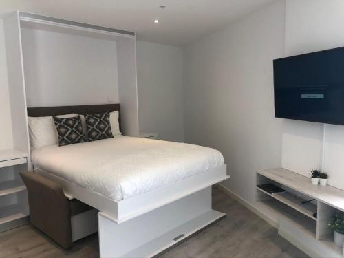 a small bedroom with a bed and a flat screen tv at CP High floor luxury studio with sea view in Gibraltar