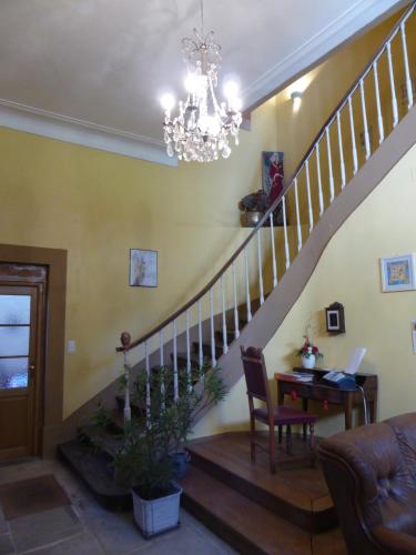 a living room with a staircase with a table and a chandelier at Maison d'hôtes Le Château de Puxe in Puxe