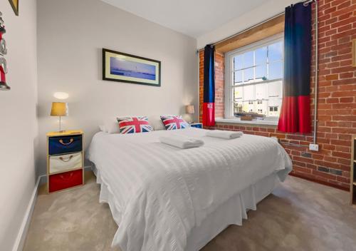 sypialnia z dużym białym łóżkiem i ceglaną ścianą w obiekcie The Granary w mieście Gosport