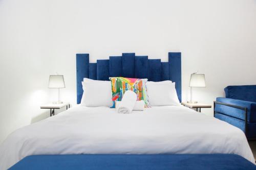 1 cama blanca grande con cabecero azul y 2 lámparas en The City Club, en Ciudad del Cabo
