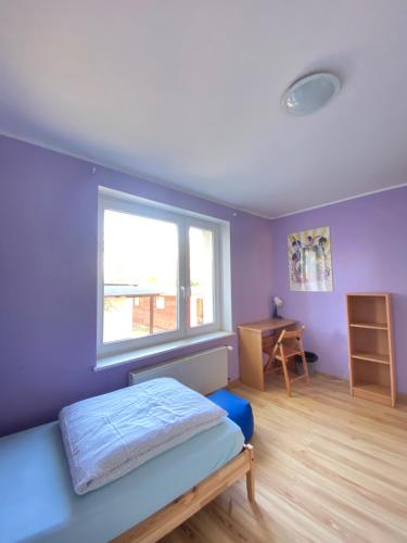 a bedroom with purple walls and a bed and a window at Hostel Mamas & Papas in Gdańsk