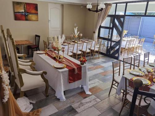 a dining room with tables and chairs and a large window at Victoria Guest Lodge in Bellville