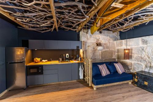 a kitchen with a blue couch in front of a stone wall at Olá Vida - Hostel Caminha in Caminha