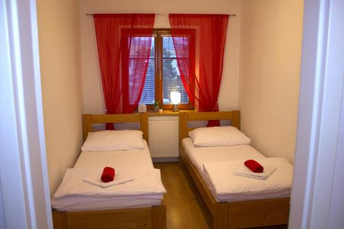 duas camas num pequeno quarto com cortinas vermelhas em Apartmany U Lva em Prachatice