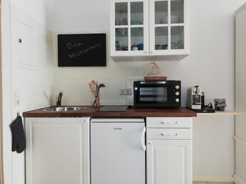 a kitchen with white cabinets and a microwave at Kajüthus Apartment 5 in Fehmarn