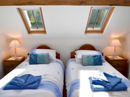 two beds in a small room with two windows at Woodhouse Cottage in Hawarden