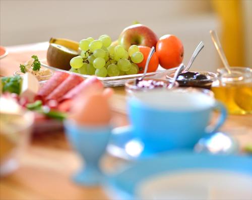 a table with a plate of fruit and a cup of coffee at Pension Onkel Ernst in Naumburg