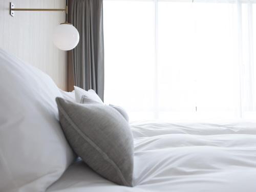 a bed with white sheets and pillows next to a window at HOTEL THE LEBEN OSAKA in Osaka
